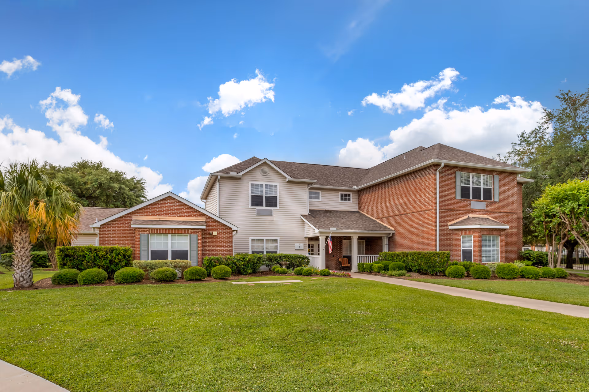 Exterior view of a brick senior living building with manicured lawn.