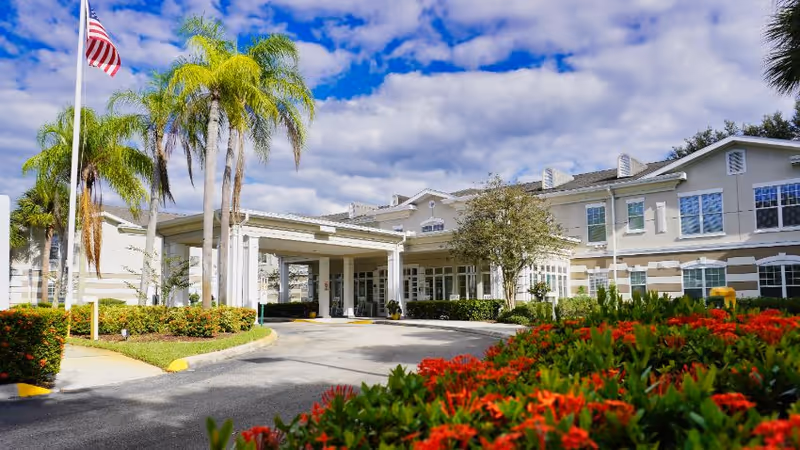 Exterior view of Sodalis Vero Beach with entrance canopy, palm trees, and colorful landscaping.
