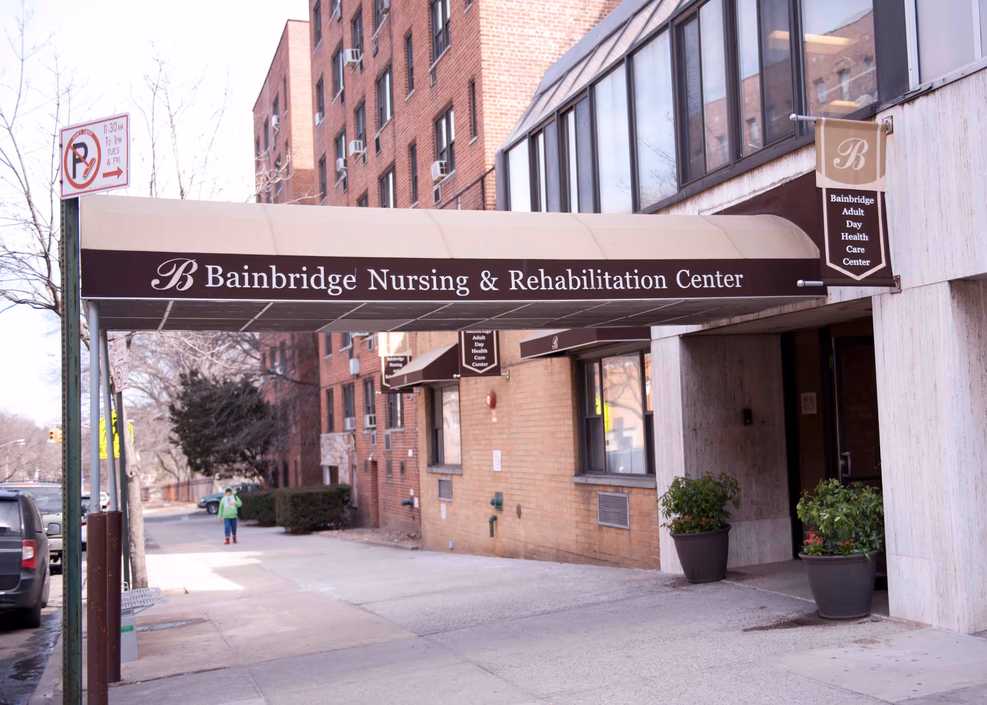 Entrance canopy reading 'Bainbridge Nursing & Rehabilitation Center' over the sidewalk at the front of a brick nursing facility.