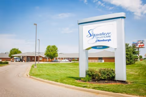 Exterior view of Signature HealthCARE of Newburgh sign with manicured lawn and building.