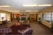 A spacious lounge with seating, a coffee table, a fireplace, and a back hallway.