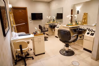 Interior salon room with styling chairs, wash sinks, mirrors, a manicure table and hair-styling equipment.