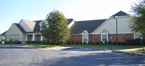 Exterior view of Oxford Springs Tulsa Assisted Living building with a curved driveway and trees.