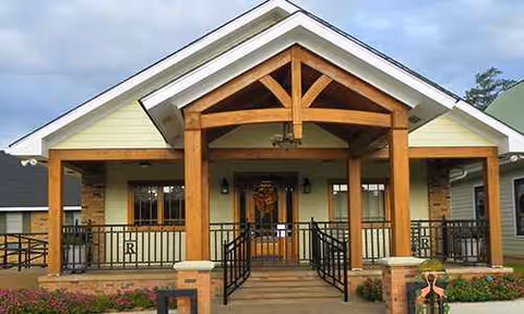 Front entrance of Resthaven Living Center Ltd with wooden porch, beams, and railing.