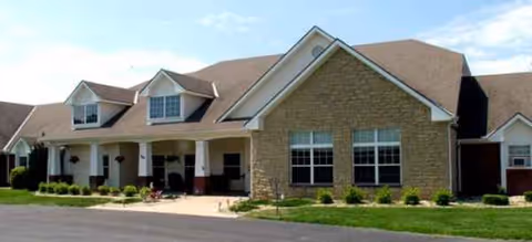 A single-story brick senior living facility with a front entrance and manicured lawn.