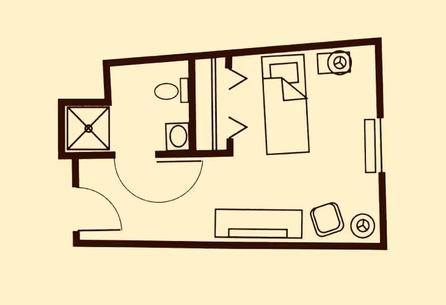 Floor plan of a small living space showing a bedroom area with a bed, a closet, a bathroom with a toilet and shower, and a small living area with a chair and table.