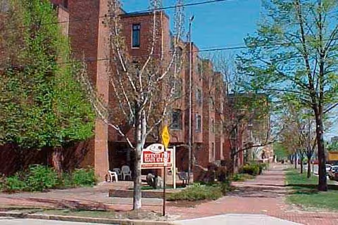 Exterior view of 75 State Street senior living building with trees and a walkway.