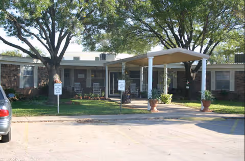 Front view of Cedar Manor Nursing & Rehab with a covered entrance and trees.