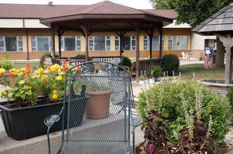 Outdoor courtyard at Four Winds Manor featuring a gazebo, flowering planters, and seating.