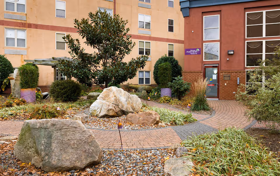 Landscaped courtyard with brick walkways, decorative rocks and plants leading to the entrance of The Manor at Market Square building.