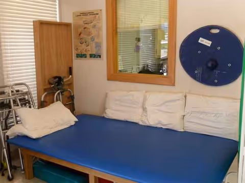 A compact nursing bedroom with a blue mattress, white pillows, and medical equipment.