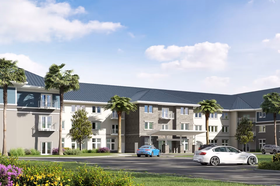 Exterior view of a modern three-story senior living facility with a blue roof, palm trees, and a parking lot with cars in front under a partly cloudy sky.