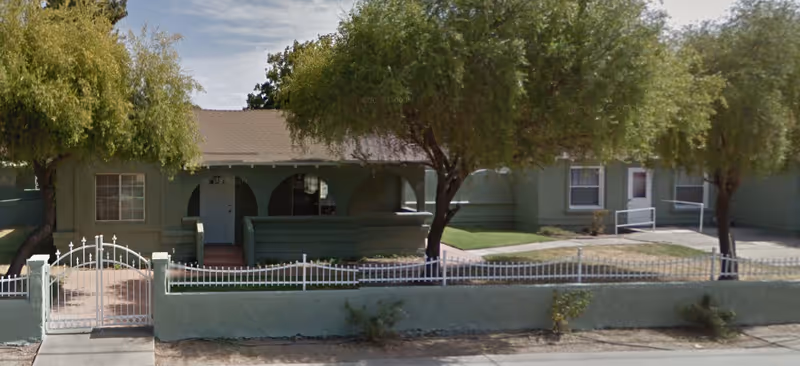 Front exterior view of a green Lifespring Senior Campus building with a small porch and trees.