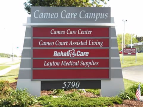Large outdoor campus sign reading 'Cameo Care Campus' with red panels listing Cameo Care Center, Cameo Court Assisted Living, Rehab & Care, Layton Medical Supplies and the address 5790.