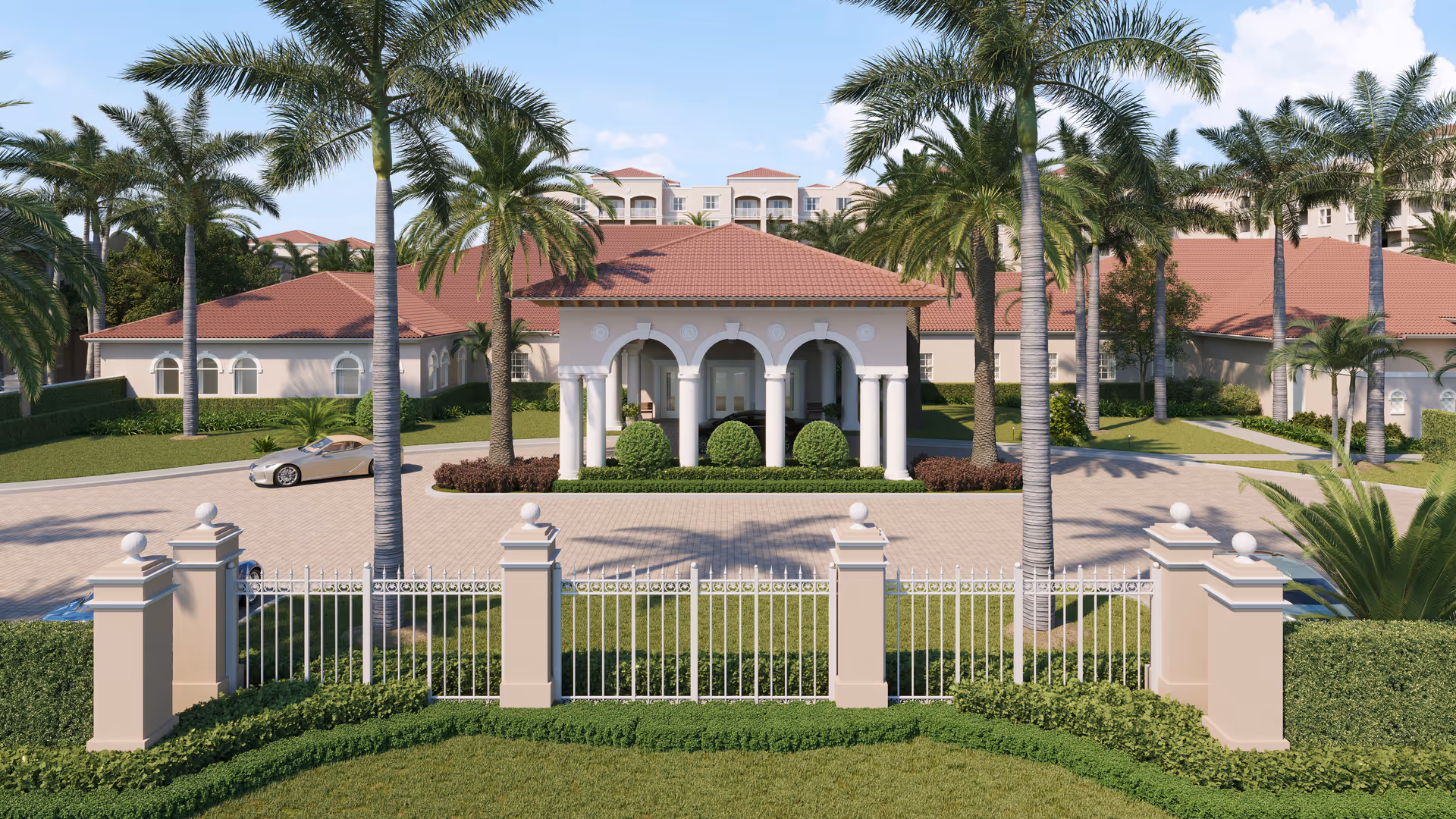 Front entrance of a Mediterranean-style assisted living facility with a gated driveway, palm trees, and red tile roofs.