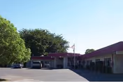 Single-story care center building with purple roof overhang, parking lot, and flag at front.