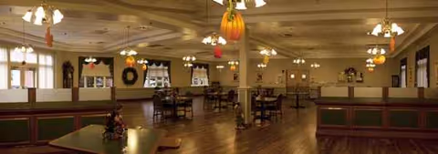 Empty dining room in a senior facility with wood floors and festive hanging decorations.