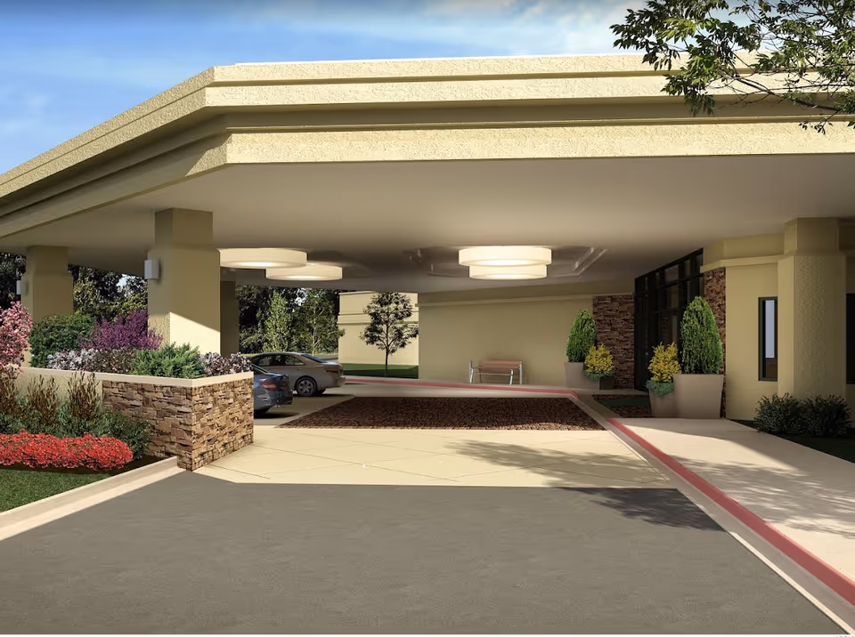 Covered entrance area of Melrose Assisted Living facility with a driveway, parked cars, decorative plants, and modern ceiling lights under the canopy.