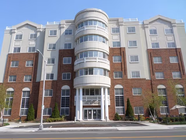 Front exterior of a multi-story brick and light-colored assisted living building with a central rounded entrance labeled "The Retreat".