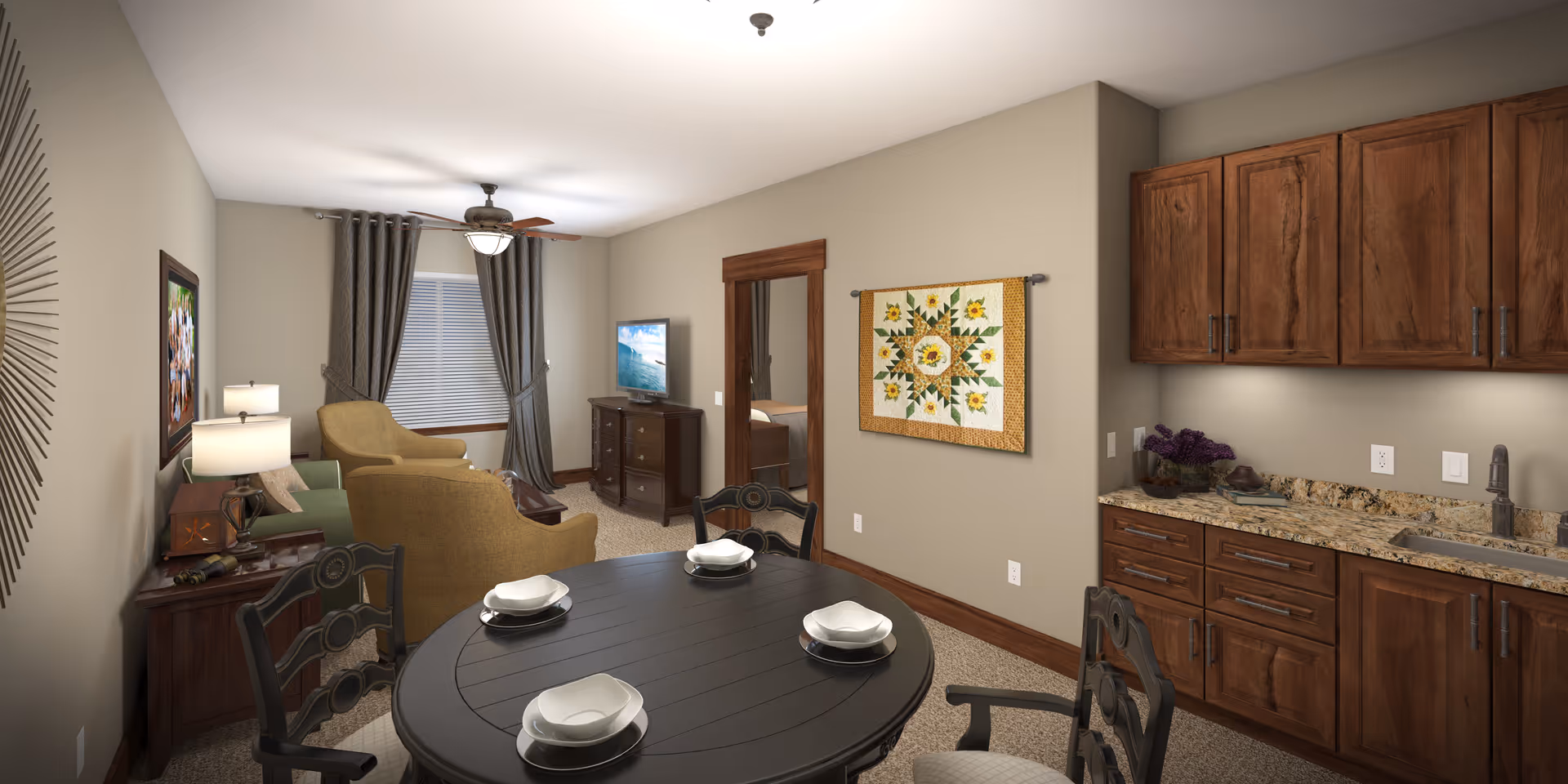 Open living area with a round dining table set for four, a seating area with armchairs and TV, and a kitchenette with wooden cabinets and granite countertops.