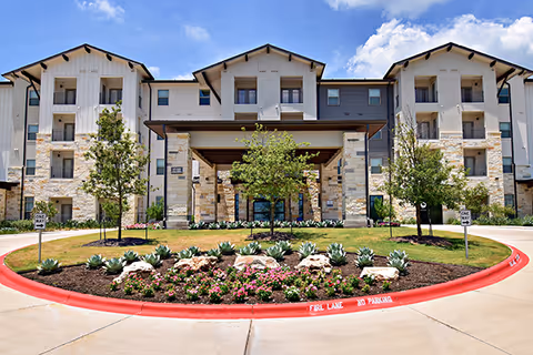 Exterior view of ArborView Circle C Ranch, a multi-story senior living building with landscaping.