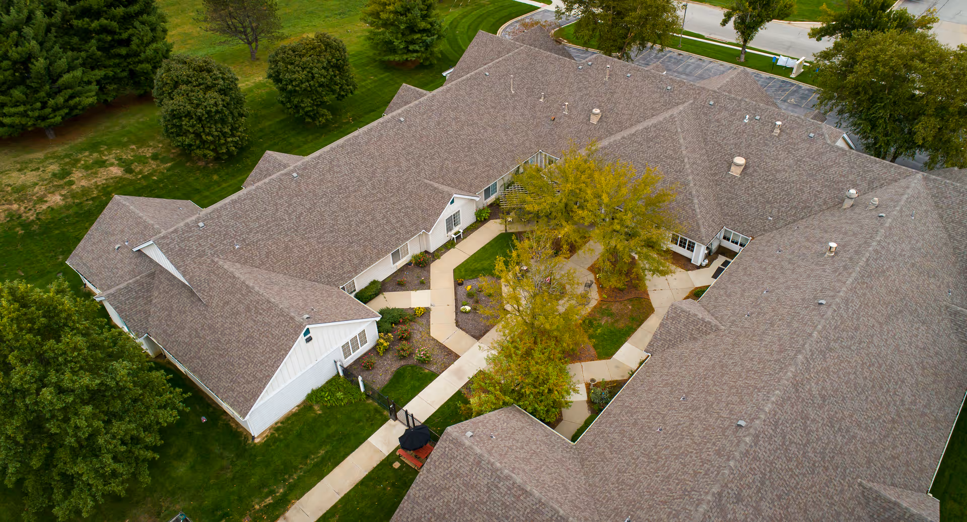 Aerial view of a single-story residential complex arranged around a landscaped central courtyard with walkways and trees.