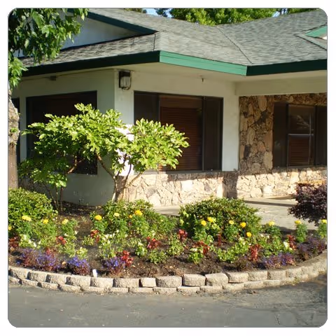 Whitney Oaks Care Center exterior with a circular flower bed and greenery