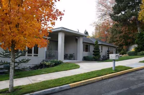 All Comfort Residential Care building with a covered entrance and autumn trees.