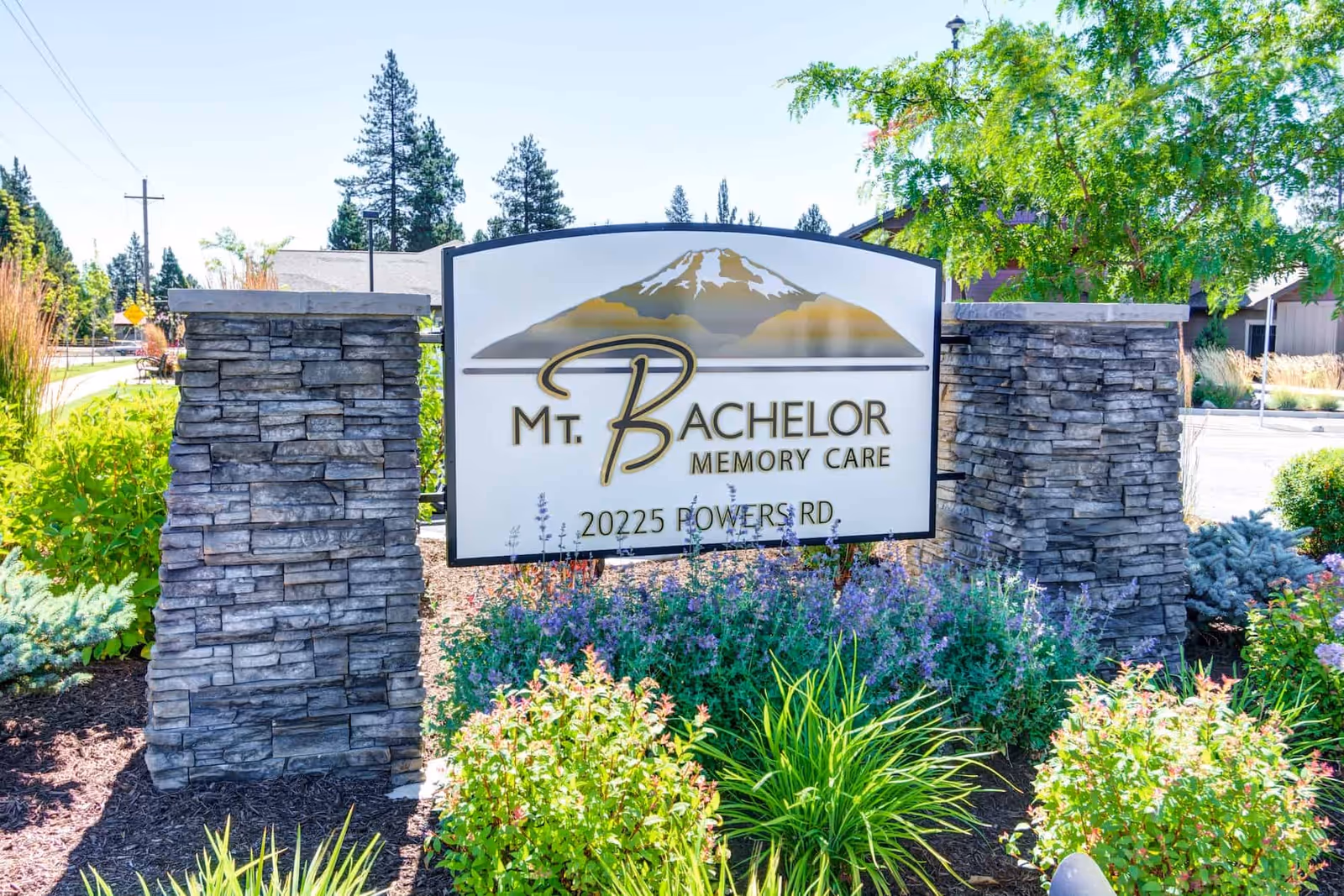 Entrance sign for Mt. Bachelor Memory Care mounted between two stone pillars with surrounding landscaping.