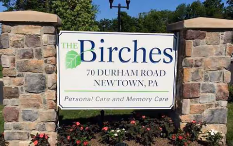 Stone entrance with The Birches sign, stone pillars, and landscaping.