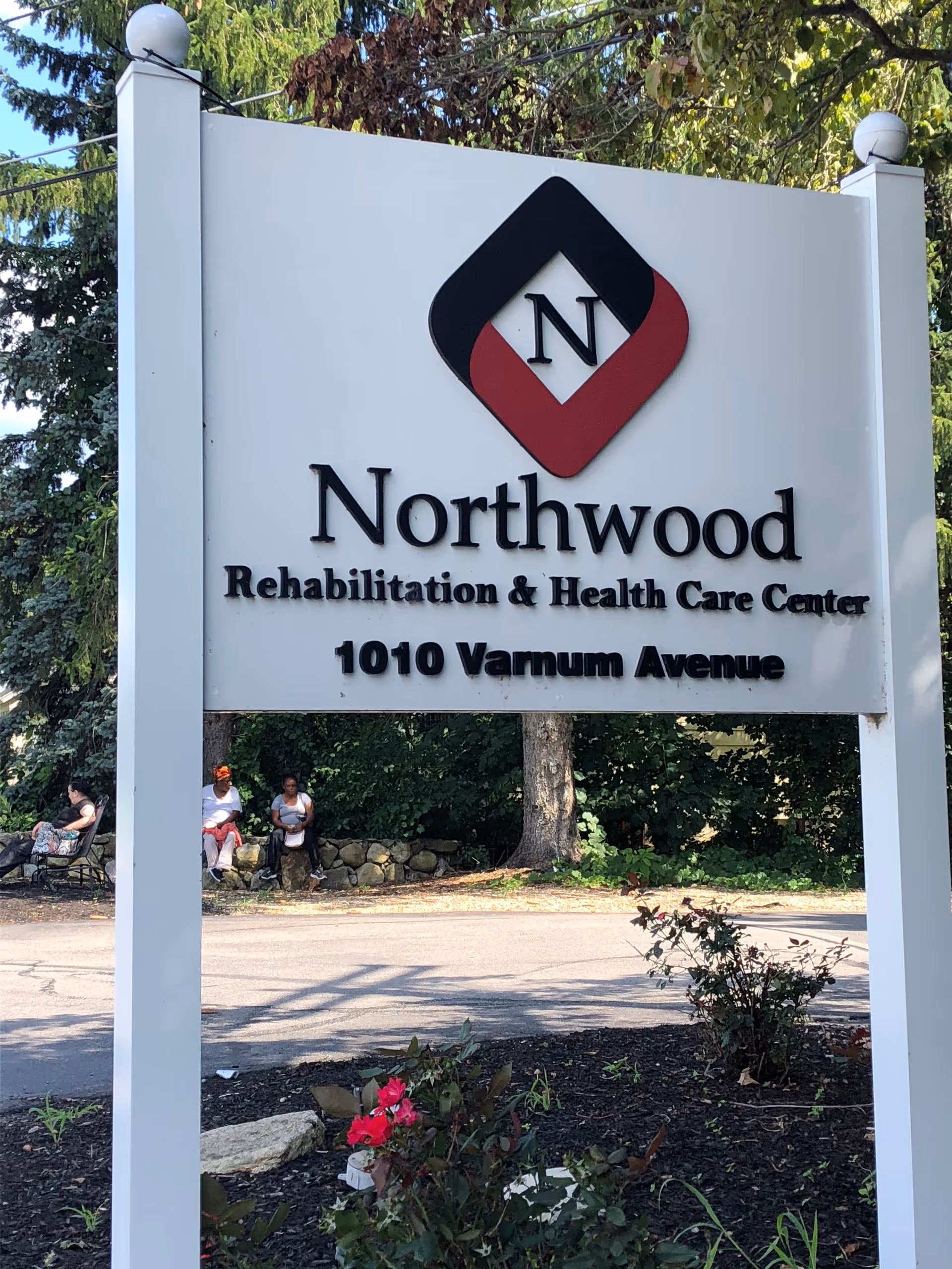 Outdoor entrance sign for Northwood Rehabilitation & Health Care Center at 1010 Varnum Avenue with landscaping and trees behind it.