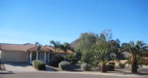 Front exterior of Valencia at 19th senior living, with driveway, entry, and palm landscaping.