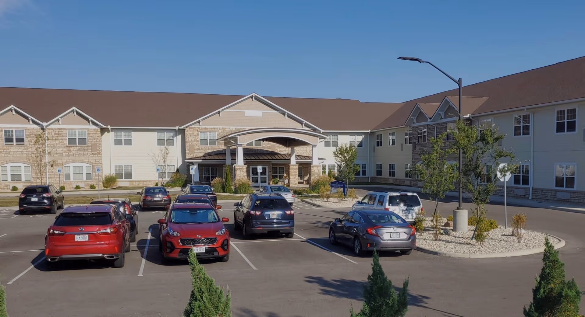 Exterior front of Norwich Springs Health Campus showing the entrance canopy, multi-story building facade, and a parking lot with several cars.