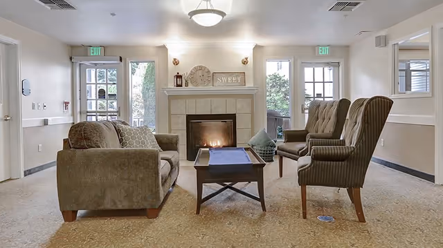 Cozy communal living room with a lit fireplace, sofa, armchairs and a coffee table.