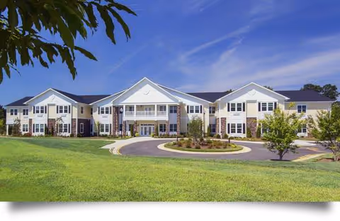 Exterior view of Cadence North Raleigh senior living facility with circular driveway and green lawn.
