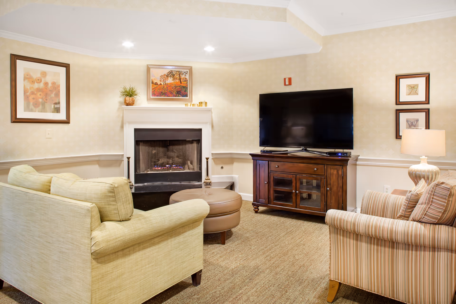 Cozy living room with sofas, a fireplace, and a large flat-screen TV on a wooden cabinet.