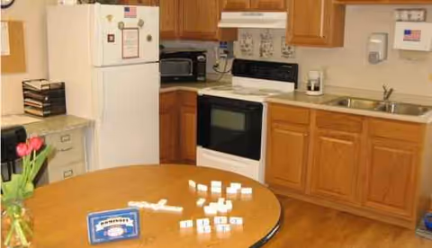 Wooden kitchen with fridge, stove, sink, and a round table with tulips.