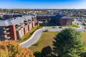 Aerial view of The Summit senior living campus with red-brick buildings, a curved driveway, landscaped lawns, and surrounding neighborhood.