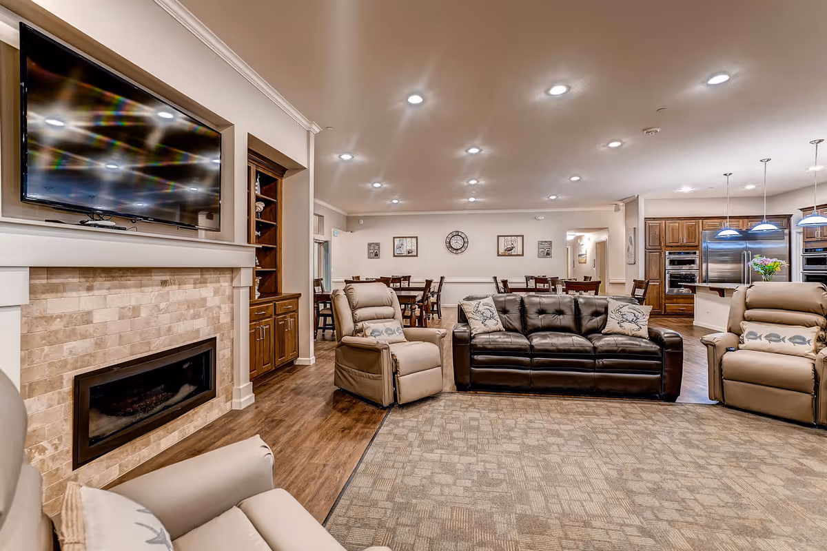 Spacious living room with leather sofas, recliners, fireplace, TV, and a dining area.
