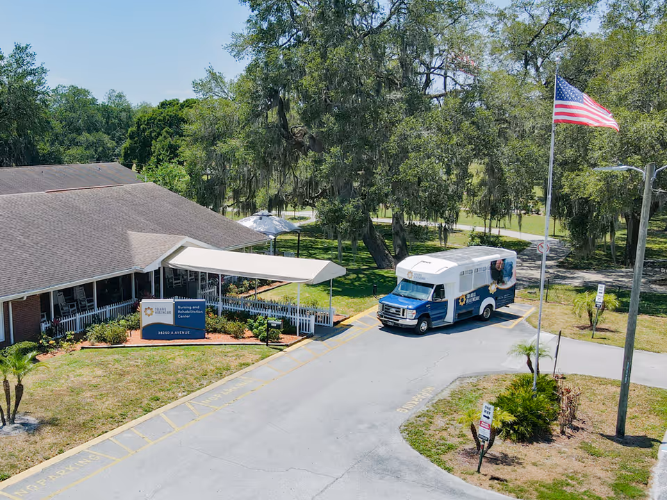 Aerial view of Solaris Healthcare Lake Zephyr's front entrance with a blue-and-white shuttle bus, sign, and surrounding trees.