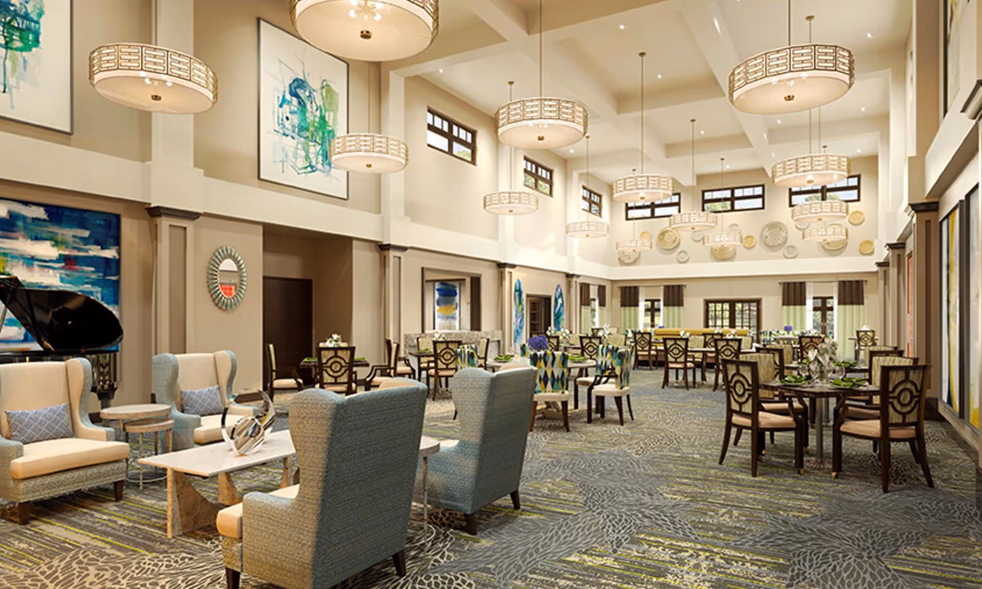 A spacious and well-lit dining room in a senior living facility with high ceilings and multiple round tables set with chairs. The room features modern chandeliers, large windows, abstract artwork on the walls, and comfortable seating areas with armchairs and small tables. The carpet has a patterned design, and the overall decor is elegant and inviting.