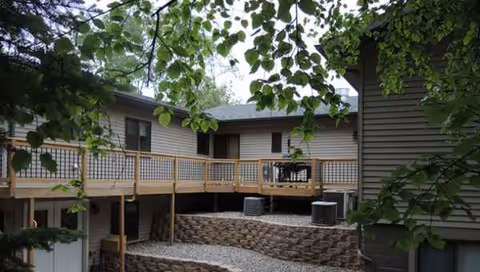 Exterior view of Vitality Living of Park Rapids with a wooden deck and trees.