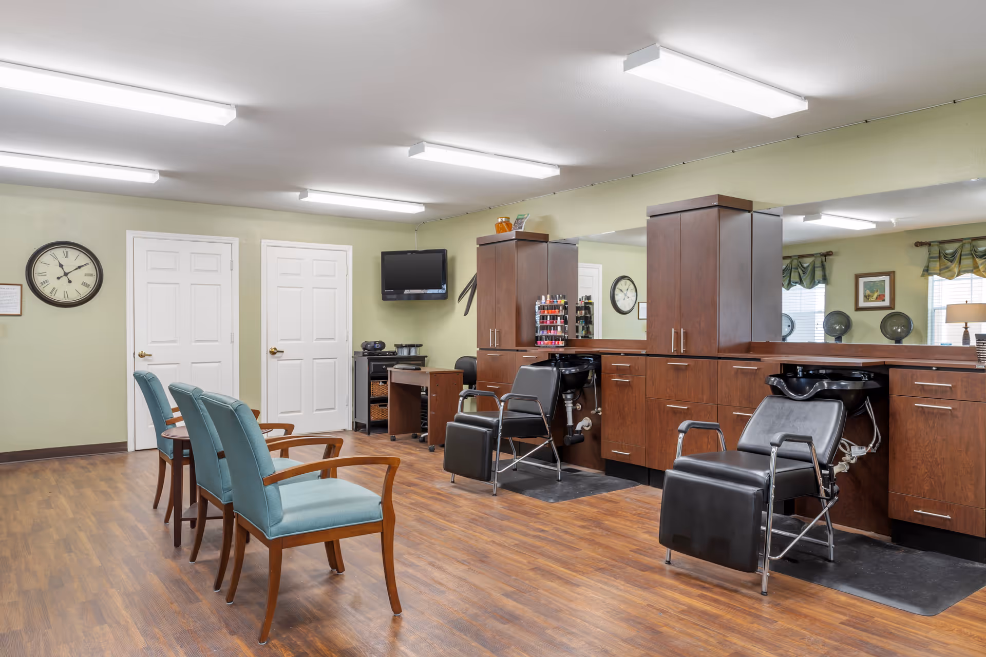 Bright salon area with styling chairs, shampoo sinks, mirrors and waiting chairs in a senior living facility.