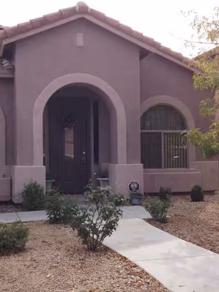Front view of a purple stucco assisted living facility with arched entryway.