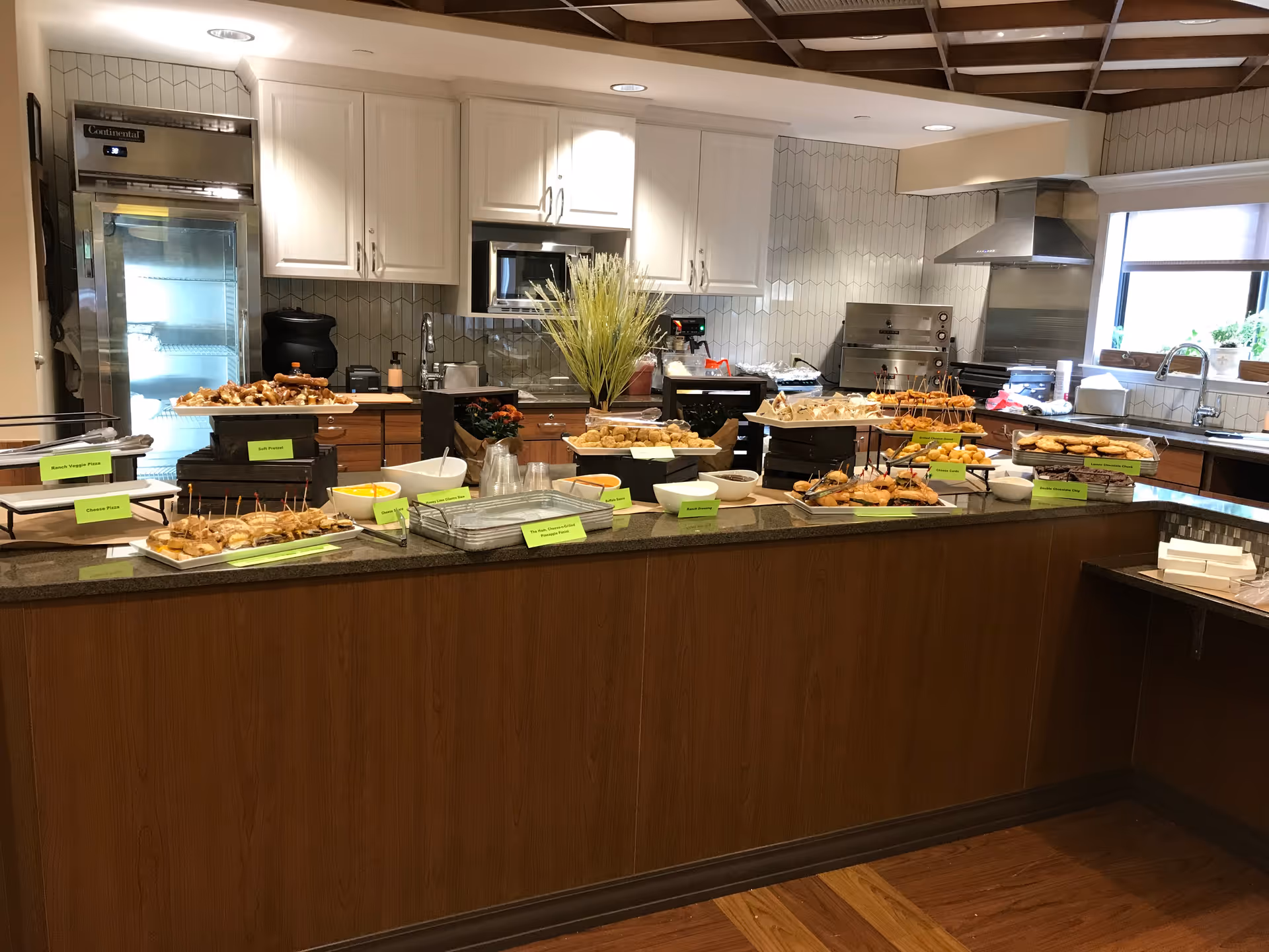 Buffet-style spread of appetizers and dishes arranged on a counter in a modern kitchen serving area.
