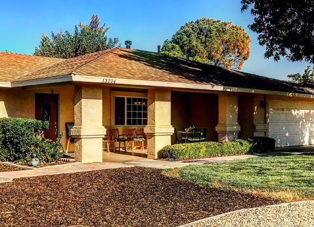 Front view of a single-story beige senior living home with porch seating.