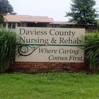 A large sign in front of a brick building that reads 'Daviess County Nursing & Rehab — Where Caring Comes First,' with grass and landscaping in the foreground.