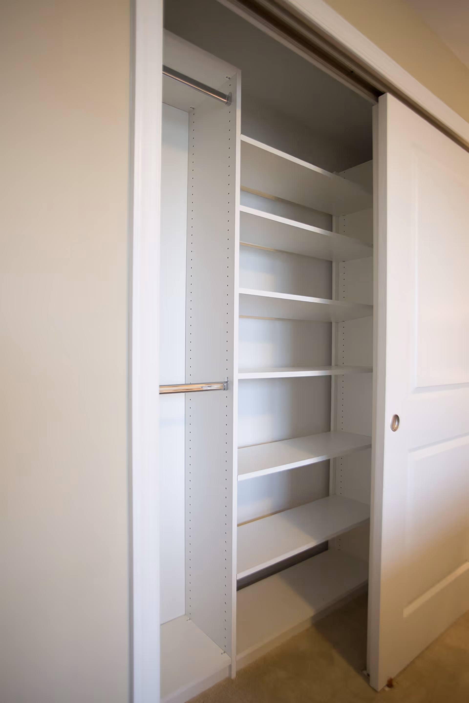 Open closet with built-in white shelving and a partially open sliding door.