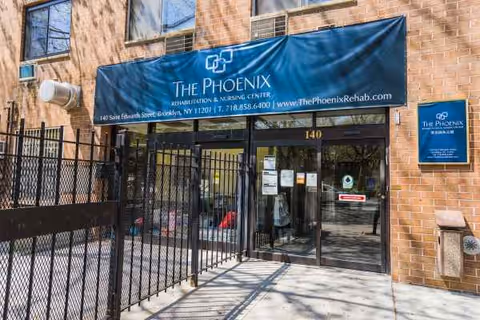 Blue awning reads The Phoenix Rehabilitation & Nursing Center above glass doors at brick building entrance.