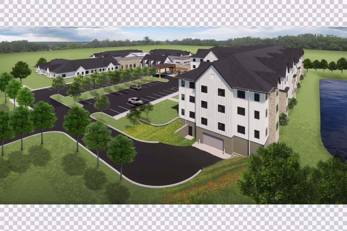 Aerial view of a senior living facility named Bryant House, showing multiple connected buildings with white siding and dark roofs, surrounded by green lawns, trees, a parking lot with a few cars, and a body of water on the right side.